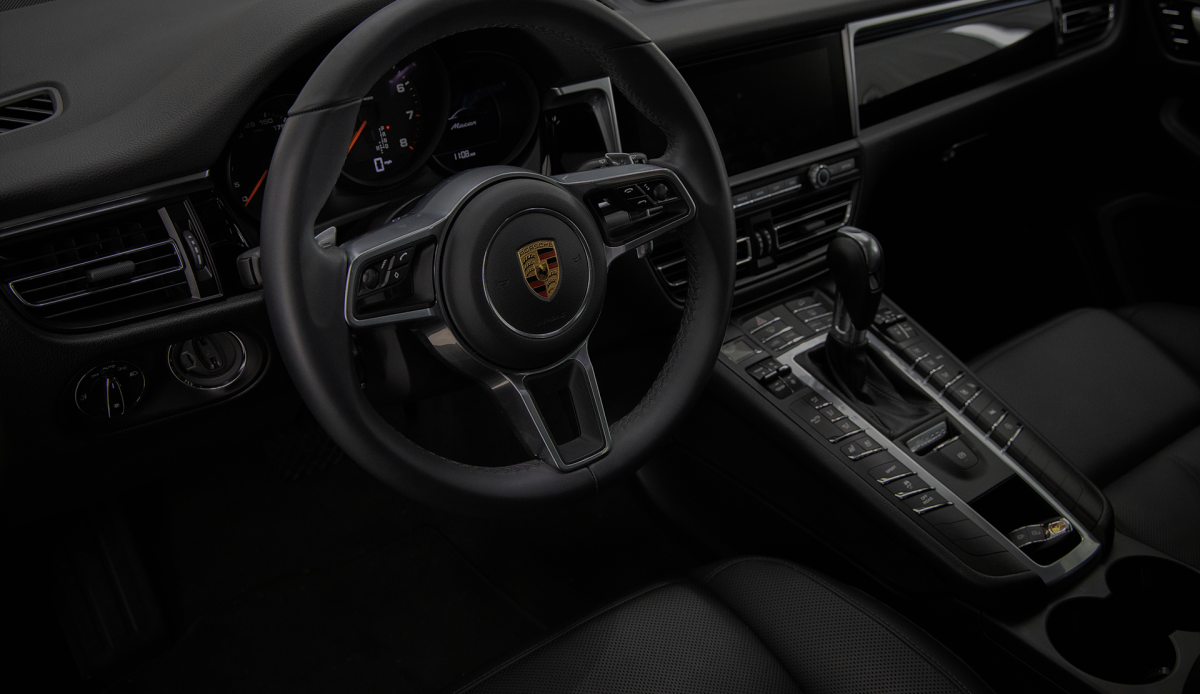 A luxury Porsche interior featuring the dashboard and steering wheel, showcasing the perfect setup for a Porsche Apple CarPlay upgrade on the factory PCM system.
